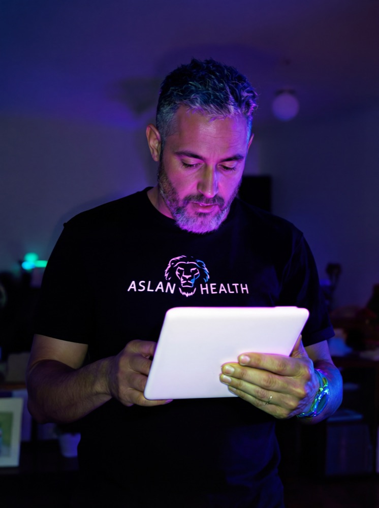 Dr. Hauman in an Aslan Health shirt reviewing the Energy Restoration Roadmap on a tablet